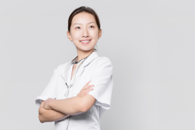 站在灰色背景前自信微笑的女医生目视前方自信微笑