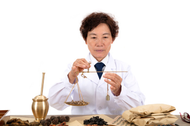 白背景前中国老中医正在配药