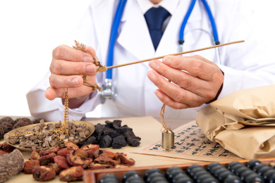 白背景前中国老中医正在配制草药