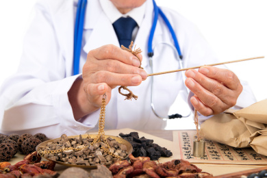 白背景前中国老中医正在配制草药