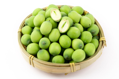 白色背景上放着一筐莲子，莲子上面放着一颗切开了能看到莲心的莲子