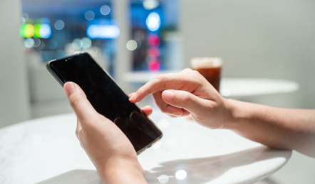 双手手拿手机在店铺里使用手机