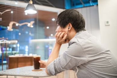 一个亚洲男性在咖啡店喝咖啡玩手机听音乐