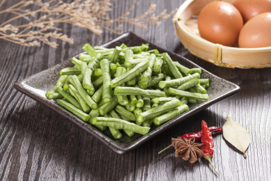 新鲜的豇豆切成段摆放在深色盘子中