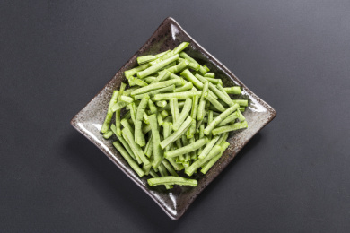 新鲜的豇豆切成段摆放在深色盘子中