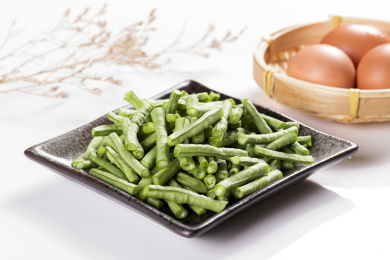 新鲜的豇豆切成段摆放在深色盘子中