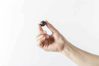 白色背景一只手拿着一颗中成药药丸特写