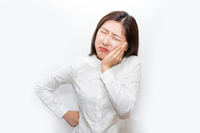 一个中国女人摸着自己疼痛难耐的牙齿
