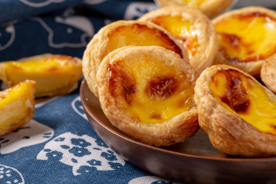 很多美食蛋挞放在花色背景布上