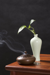 深色背景前摆放在红木桌面上的紫铜香炉