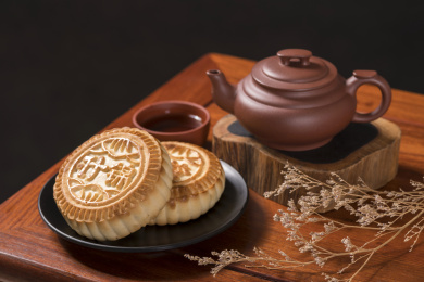 深色背景前摆放在红木桌面上的月饼