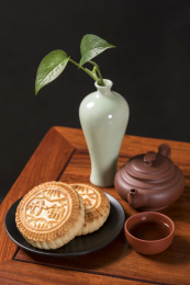 深色背景前摆放在红木桌面上的月饼