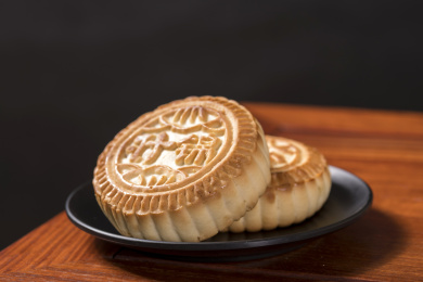 深色背景前摆放在红木桌面上的月饼