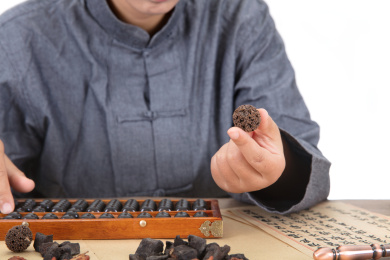 年轻的中医医生一只手打着算盘另一只手拿着中药路路通观察