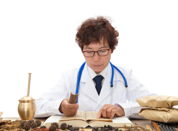 老中医拿着一块桂皮翻看中药典籍查找资料