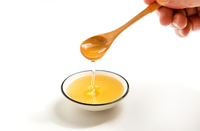 白色背景纸上的勺子和蜂蜜