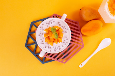 黄色背景上一碗正上方视角的芒果西米露