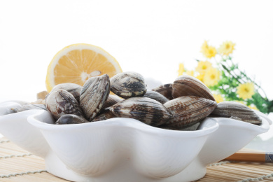 珠帘垫上白色盘子里摆放着的新鲜花蛤