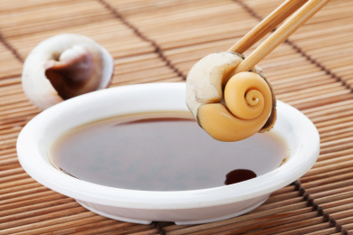 珠帘垫背景前夹在筷子上的蜗牛肉