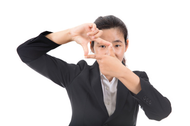 白背景前穿着正装的漂亮女士双手做出一个框的形状