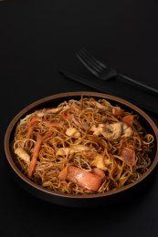 黑色桌面上的三丝炒面，和旁边的叉子筷子