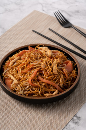 大理石桌面上的三丝炒面和旁边的筷子，叉子