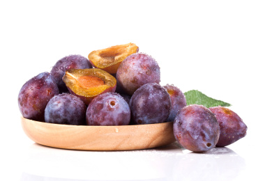 白色背景上装在盘子里的新鲜西梅