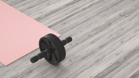 健身题材的木质地板上的塑胶健腹轮和瑜伽垫，3d渲染