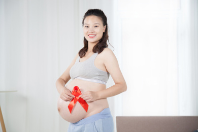 站在窗前手持红丝带的孕妇