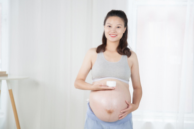 站在窗前手端化妆品的孕妇