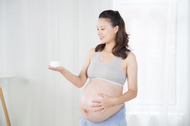 站在窗前手端化妆品的孕妇