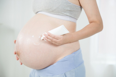 站在窗前手挤护肤品的孕妇