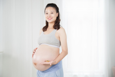 站在窗前手端金元宝的孕妇