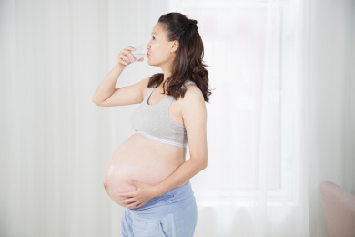 室内站立着喝牛奶的孕妇形象