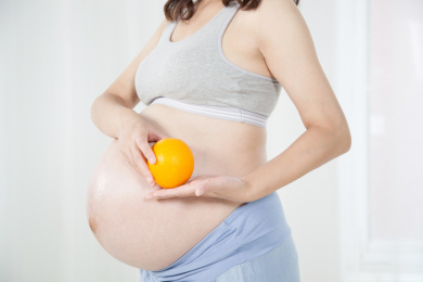 室内站立着手持橙子的孕妇