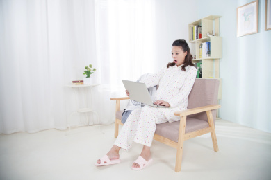 坐在沙发上用电脑上网的孕妇