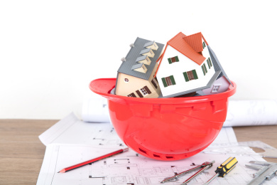 倒放的红色安全帽和帽子里塞满的小房子模型