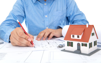 建筑设计师在看图纸及一旁放着一个小房子模型