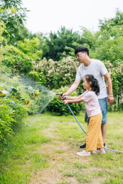 父亲和女孩在后院给植物和草坪浇水