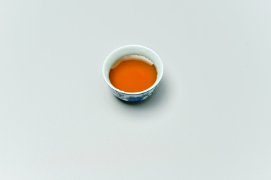 浅灰色背景下的一杯中式茶杯里的普洱茶特写