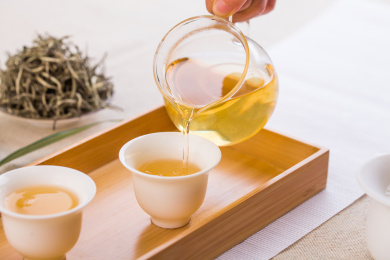 中式茶席上木托盘里的白瓷杯里的茶汤