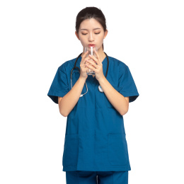 白色背景里，身穿蓝色手术服正在喝水的年轻女医师