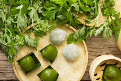放在竹编筐里的清明美食青团，旁边还放着植物艾草