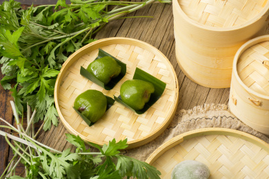 放在竹编筐里的清明美食青团，旁边还放着植物艾草