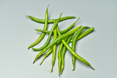 一堆绿色的辣椒尖椒的摆放在灰色背景上