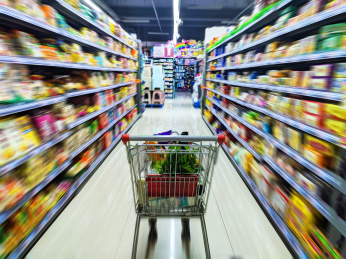 超市购物车在放满商品的动态模糊效果的货架中间