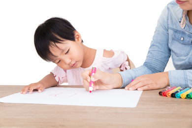 年轻的妈妈或幼教老师在耐心的教小孩子画画