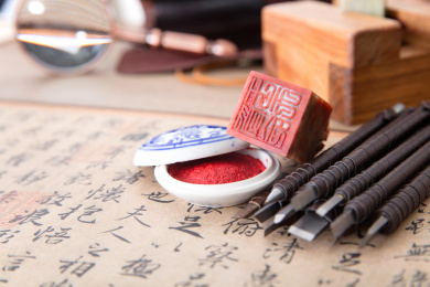一堆刻刀和一枚石质印章及印泥和书法作品