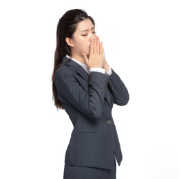  白色背景里，身穿西服身体不舒服的美丽商务女士