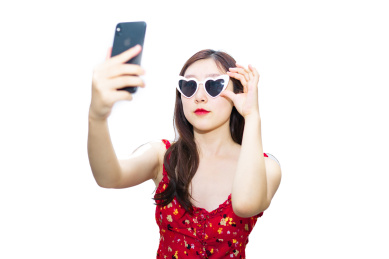 夏季一个中国女孩拿着手机戴着墨镜正在自拍拍照